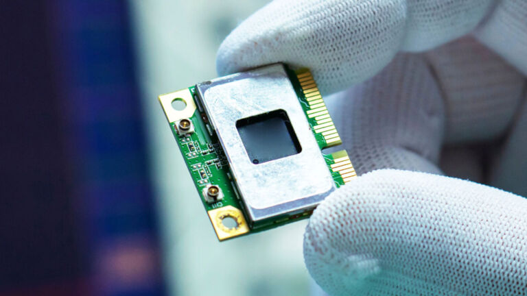 Gloved fingertips holding semiconductor chip